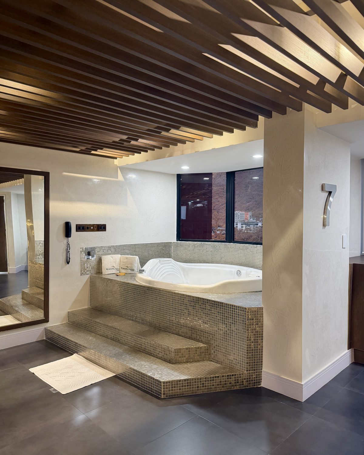 Seven: jacuzzi sobre escalones de mosaico dorado junto a la ventana