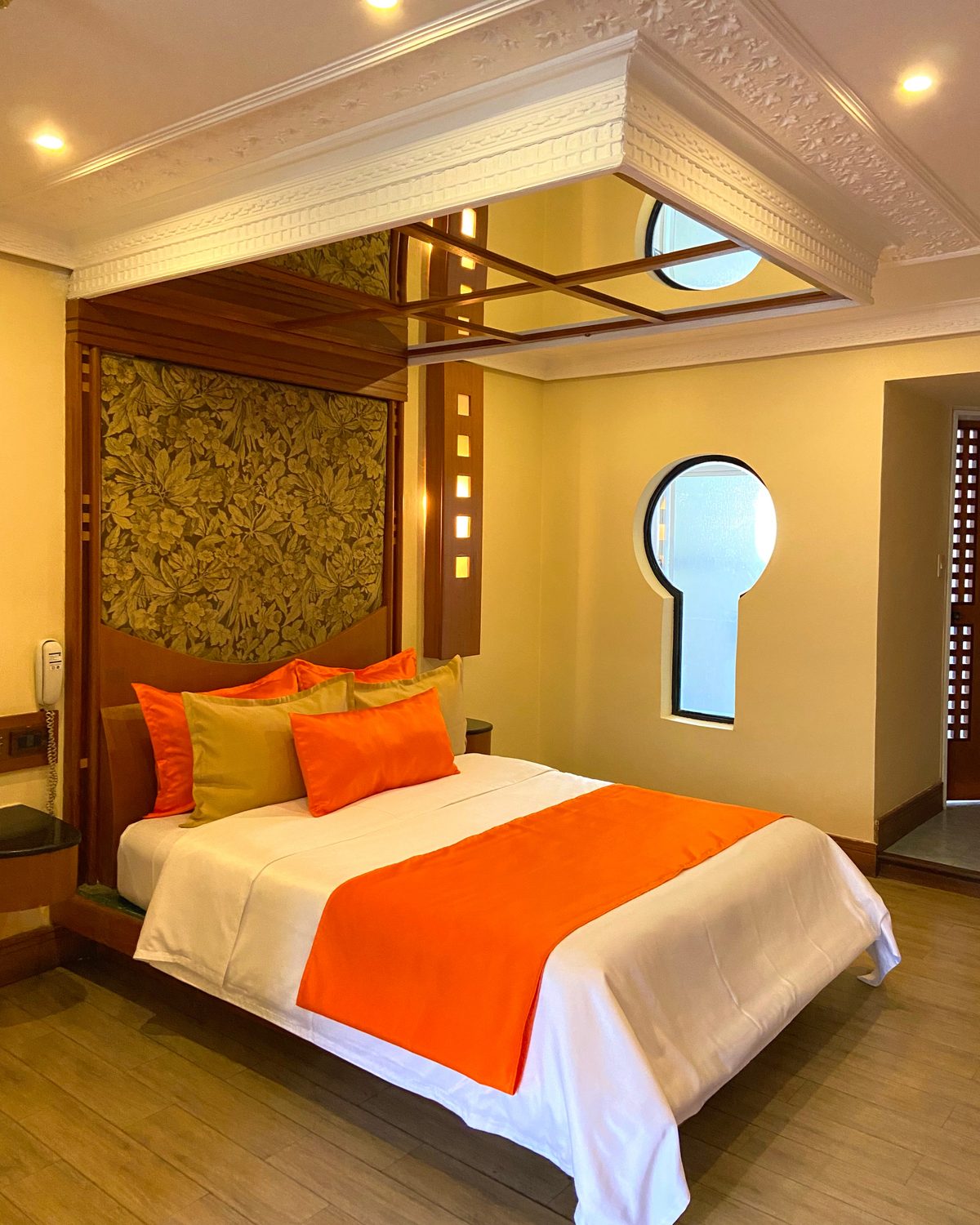 Japonesa Premium: cama con cubrecama naranja, cabecero de tapiz de hojas y ventana en forma de cerradura