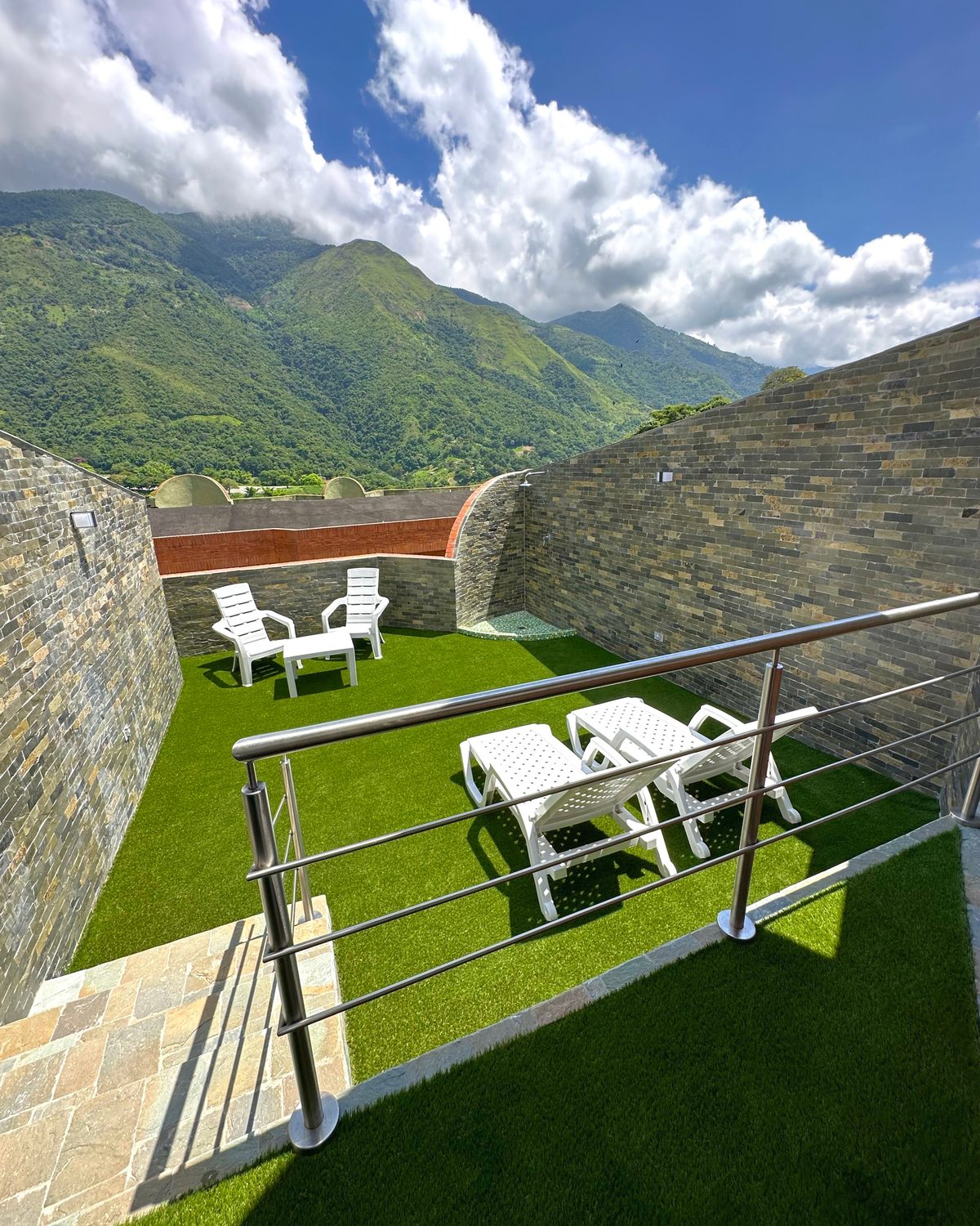 Zen con Terraza: terraza privada con grama, tumbonas y vista a la montaña